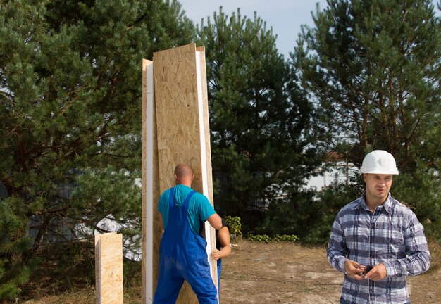 construction-workers-busy-erecting-corner-insulated-wooden-wall-panel-engineer-site-working-new-house-build_385506-3158