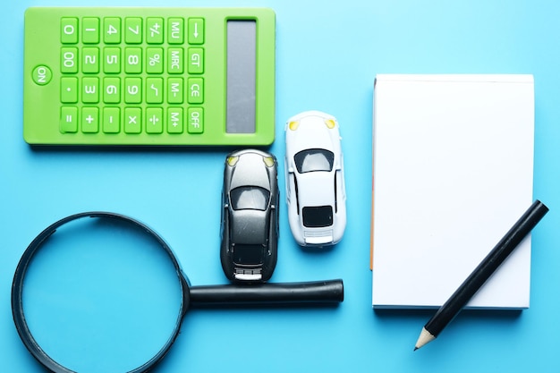 flatlay-picture-magnifying-two-cars-miniature-notepadpencil-calculator-best-deal-car-drive_1164969-166