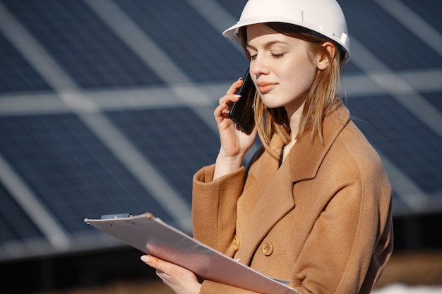 solar-energy-station-young-female-engineer-work-plant-she-is-talking-by-phone-anddoing-business-woman-helmet-with-papers_1157-47842