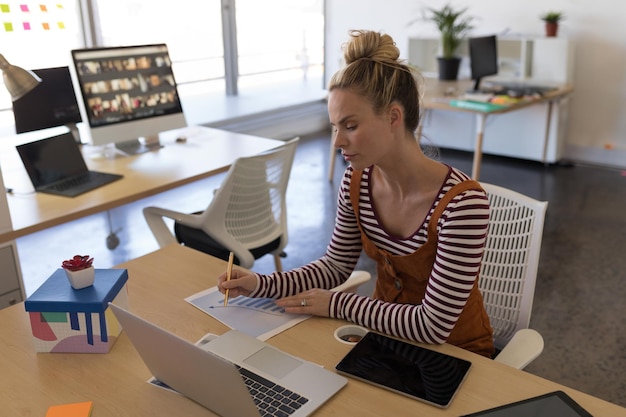 woman-office-writing-notes-while-using-laptop-video-conference_13339-380946